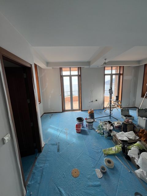 Materiel et pots de peinture prepares sur chantier de renovation avec vue mer